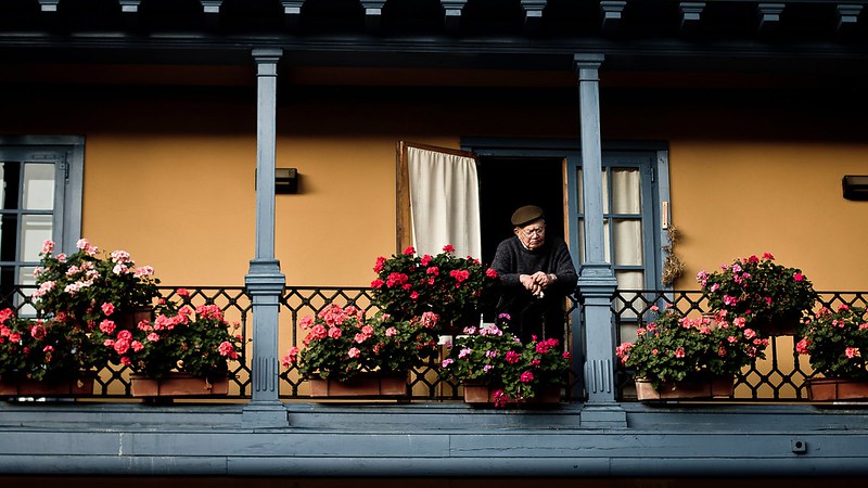 Imagen de una persona de la tercea edad asomada al balcón